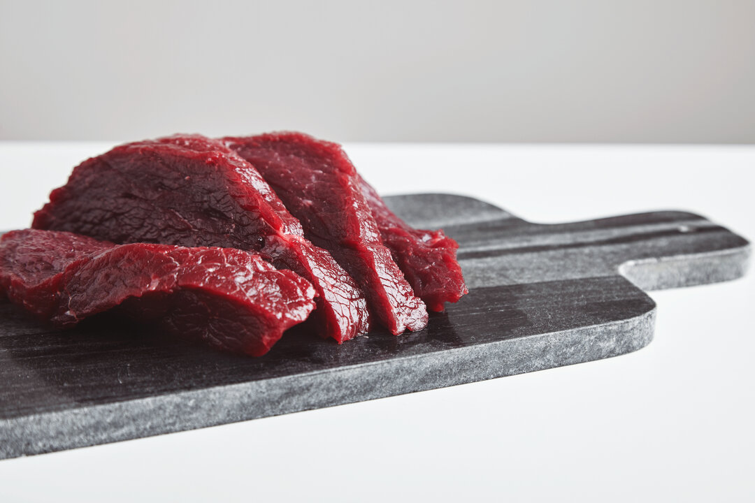 sliced-premium-raw-whale-meat-steak-marble-stone-cutting-board-isolated-white-table